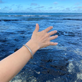 The Forged by the Ocean ladies Sterling Silver Cuff Bangle on model image with an ocean view.
